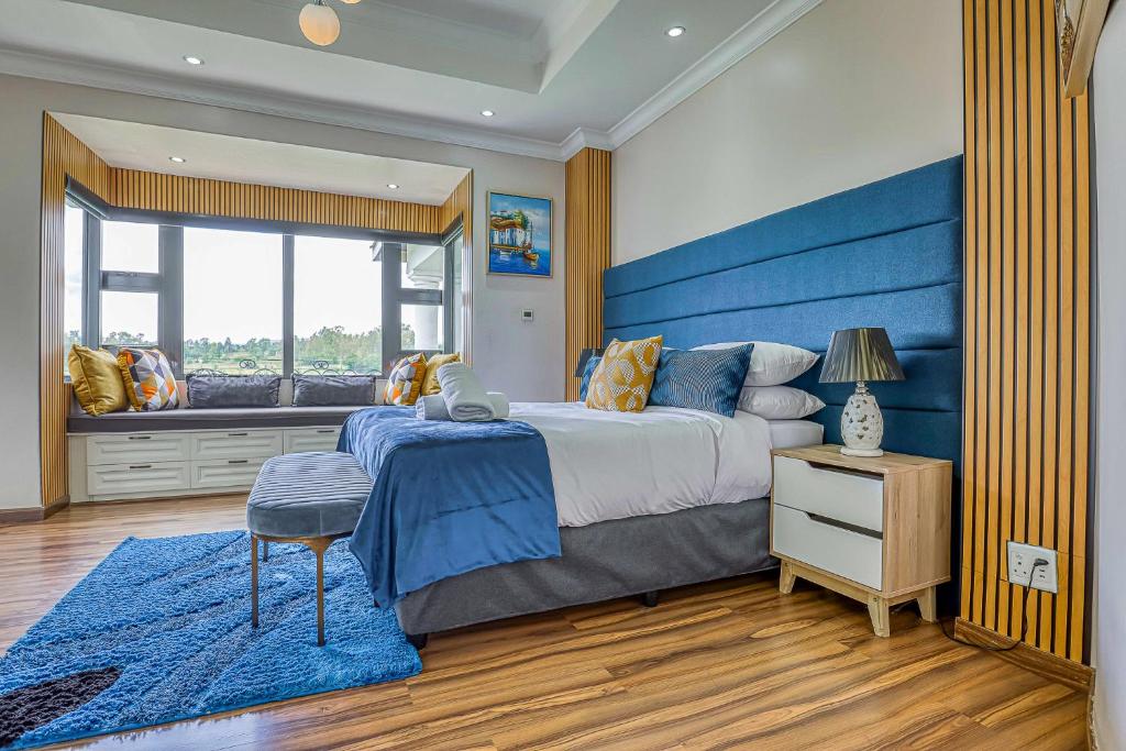 1 dormitorio con 1 cama grande y cabecero azul en Villa Tasha Luxury Suites, Lanseria, en Johannesburgo