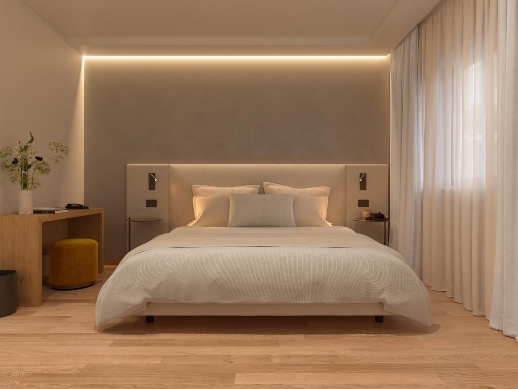 - une chambre avec un grand lit et un couvre-lit blanc dans l'établissement Naturae Lodge, à Alleghe