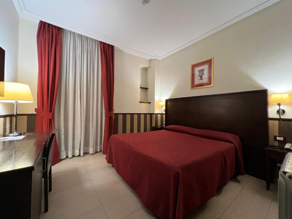 a hotel room with a red bed and a desk at Hotel Garda in Rome