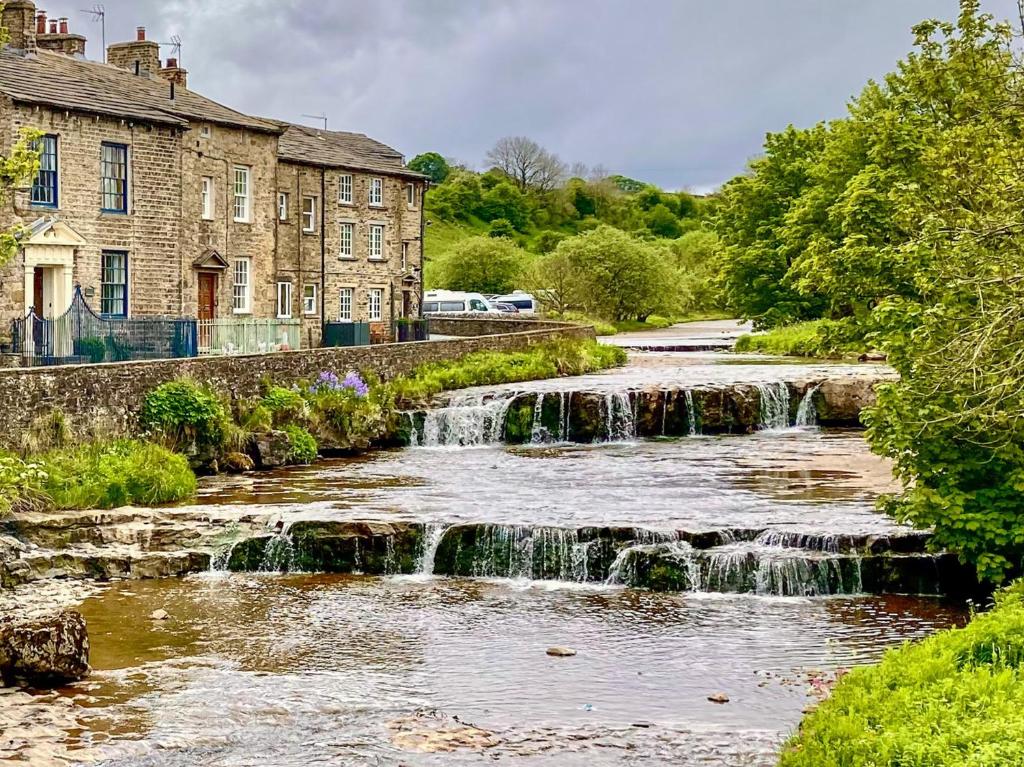a river with a waterfall in front of a building at 3 Bed in Hawes 90749 in Hawes