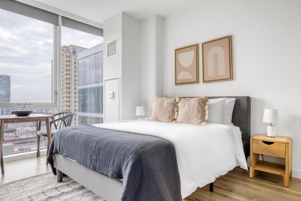 a white bedroom with a bed and a large window at South Loop studio w pool gym nr Grant Park CHI-857 in Chicago