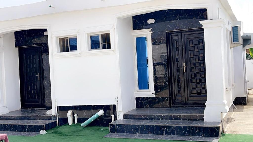 a white house with black doors and green grass at bdream home / dreamz apartment in Agege