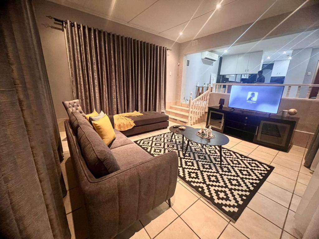a living room with a couch and a television at When in the Middle Self Catering Guest House in Durban