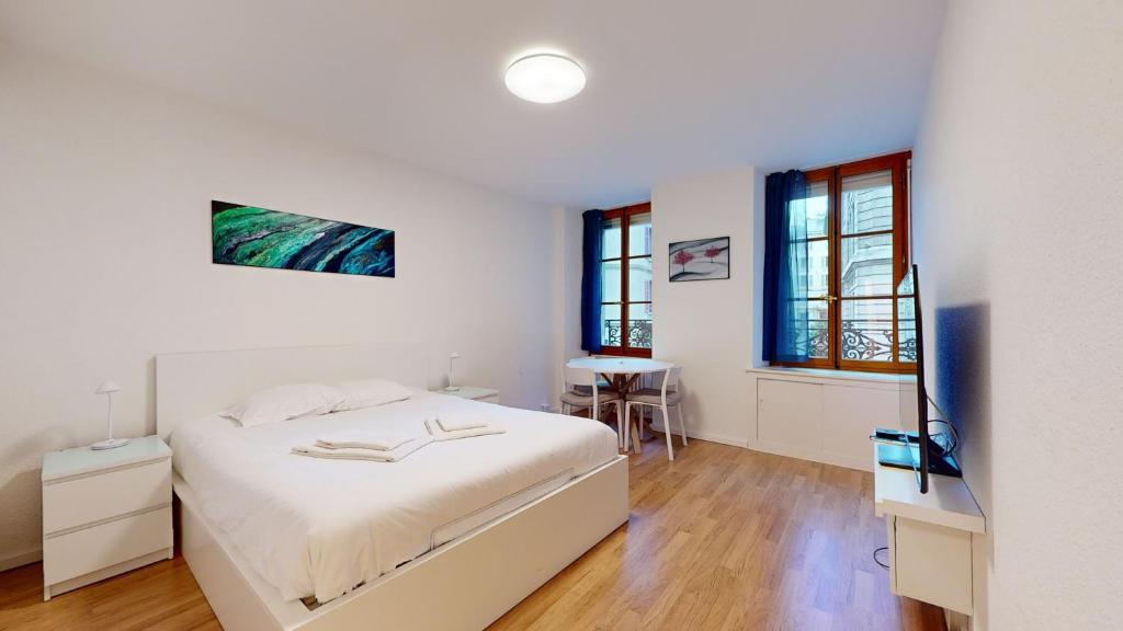 a white bedroom with a bed and a table at Modern studio in the heart of Geneva in Geneva
