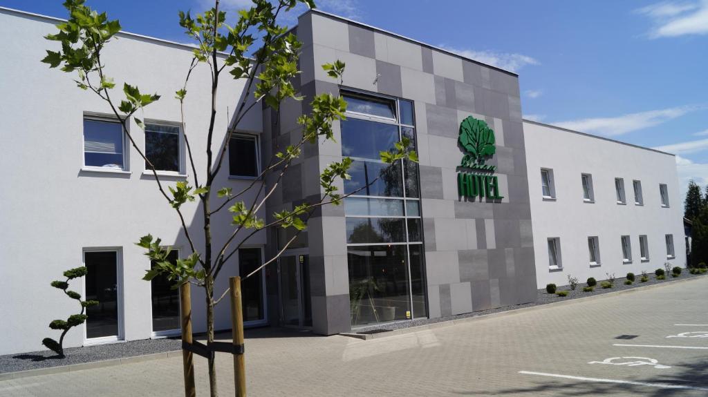 a building with a tree in front of it at Hotel Platan in Ostrów Wielkopolski