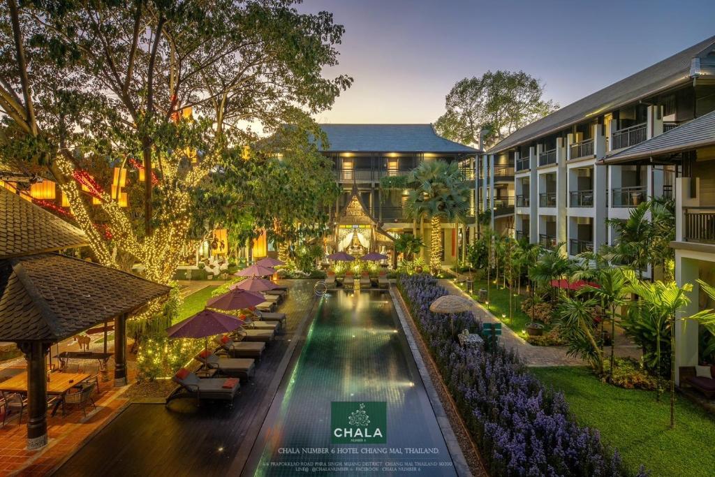 uma vista exterior de um hotel com uma piscina e guarda-sóis em Chala Number6 em Chiang Mai