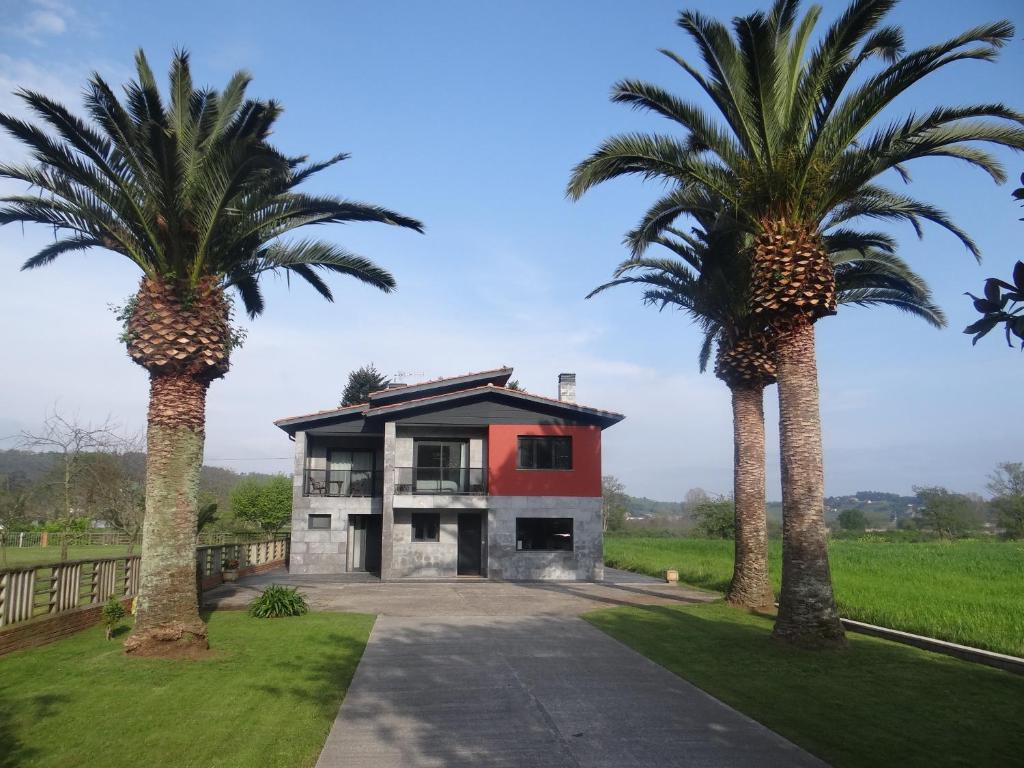 a house with two palm trees in front of it at La Casa de la Ría in Collera