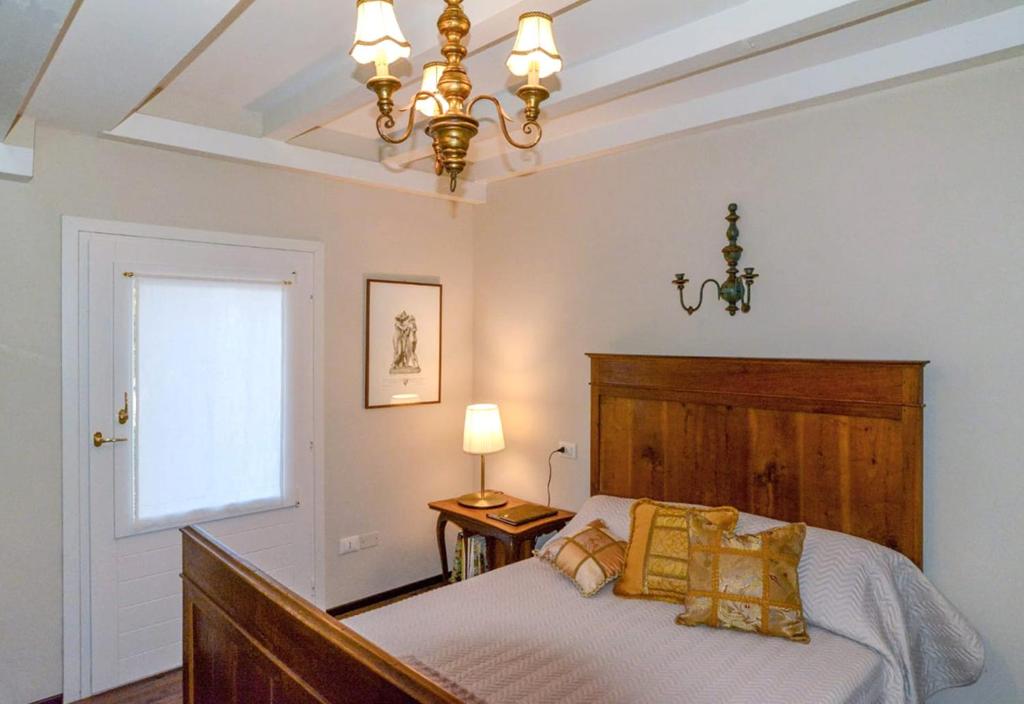 1 dormitorio con cama, ventana y lámpara de araña en i Torretti Locazione Turistica, Ristorante, Lounge Bar, en Asolo