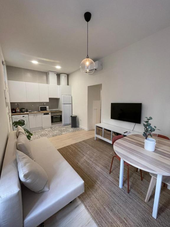 uma sala de estar com um sofá branco e uma mesa em Bajo Duplex 7pax a 5 min de Gran Via-Malasana em Madri