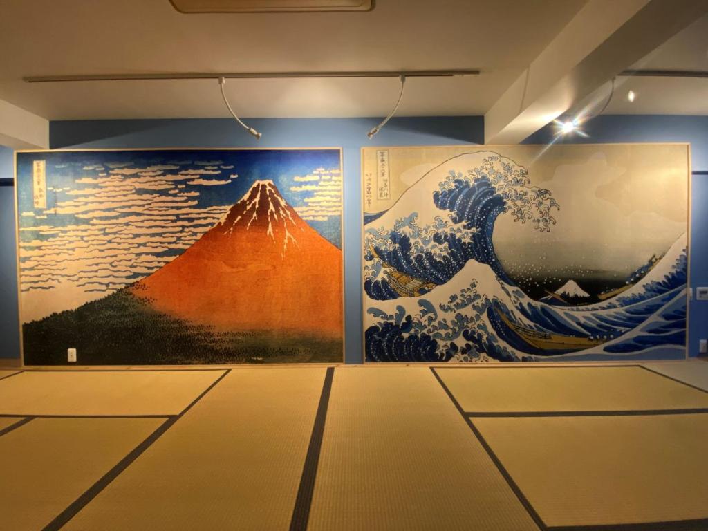 ein Zimmer mit zwei Gemälden einer Welle an der Wand in der Unterkunft Osaka Ukiyoe Ryokan in Osaka