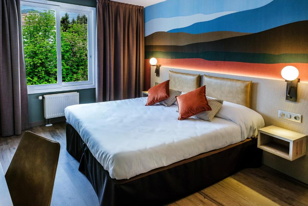 a hotel room with a large bed with pillows at Hôtel La Solitude in Lourdes