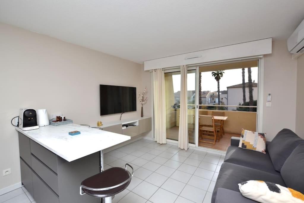 une cuisine et un salon avec un canapé et une table dans l'établissement Le Mayflower sous les palmiers, au Grau-du-Roi