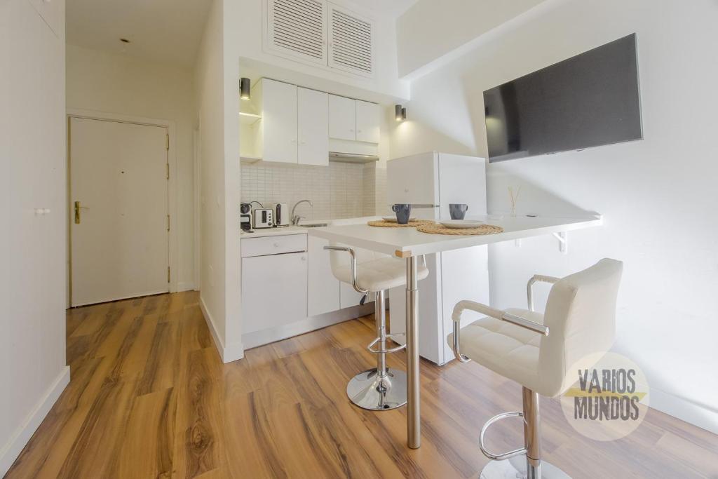 een keuken met witte kasten en een tafel en stoelen bij Downtown Apt 1hab para 3pax en la Plaza de Chueca in Madrid