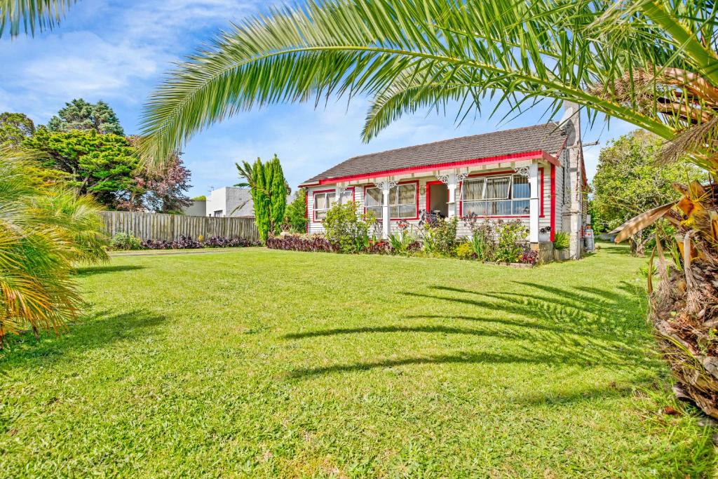 uma casa com uma palmeira em frente a um quintal em Miami Stay em Auckland