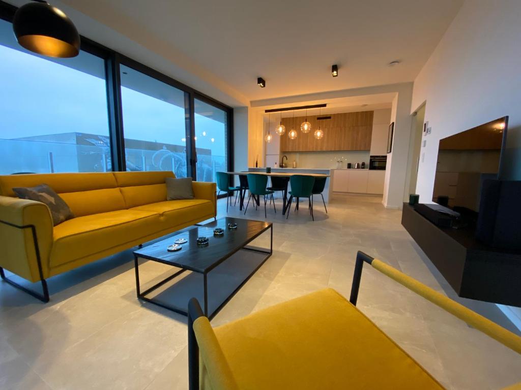 un soggiorno con divano giallo e tavolo di Casa Aninka a Ostenda
