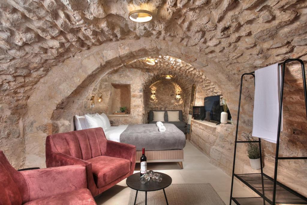 1 dormitorio en una habitación con paredes de piedra, 1 cama y 1 silla en סוויטת גן עדן - Gan Eden Suite, en Safed