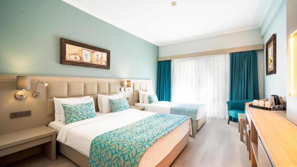 a hotel room with two beds and a desk at Aqua Fantasy Aquapark Hotel & Spa - Ultra All Inclusive in Kusadası