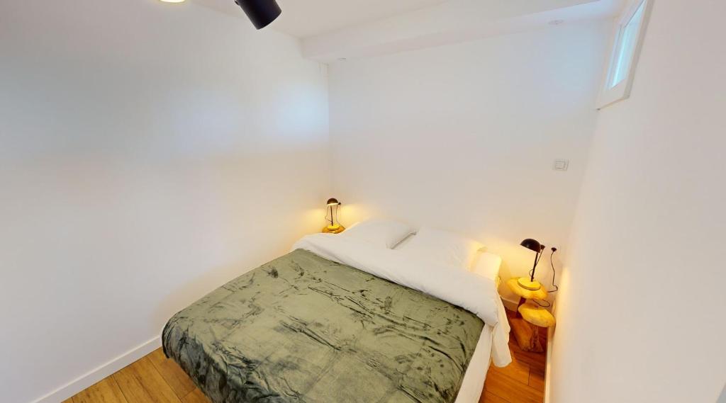 een kleine slaapkamer met een bed in een witte muur bij Les meublés touristiques - Saint Théodore en face du Louvre-Lens in Lens