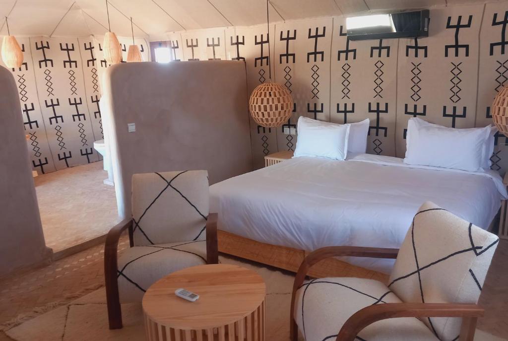 1 dormitorio con 1 cama y sillas en una habitación en Night sky luxury camp, en Adrouine