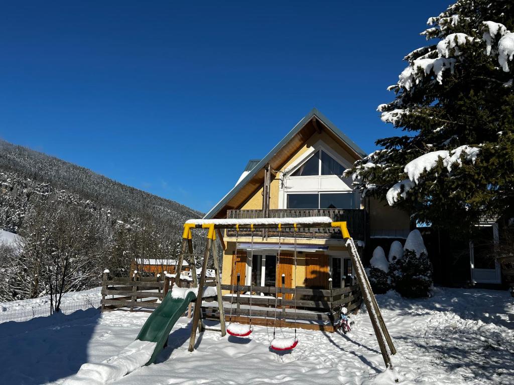 維拉爾－德朗的住宿－Chalet de Montagne Villard de Lans，雪中房子前面的游乐场