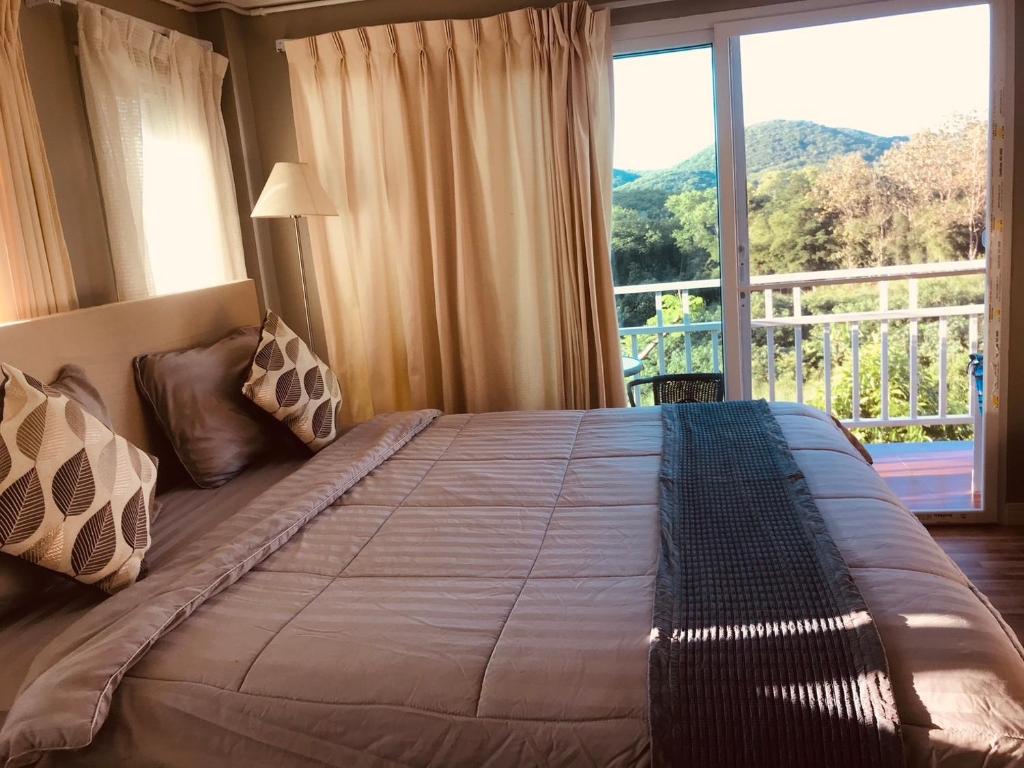 een slaapkamer met een groot bed en een groot raam bij บ้านบนภู ปากช่อง พลูวิลล่า - with a housekeeper in Ban Lam Thong Lang