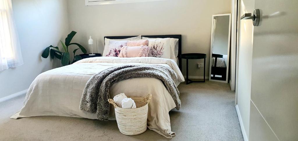 een slaapkamer met een bed met roze kussens en een mand bij Ballarat Holiday Homes - Lake Wendouree - Near Ballarat Grammar - 3 kms to Ballarat Hospitals in Ballarat