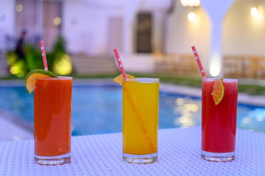 a group of three cocktails on a table next to a pool at Tvessa - A Boutique Hotel in Mandrem