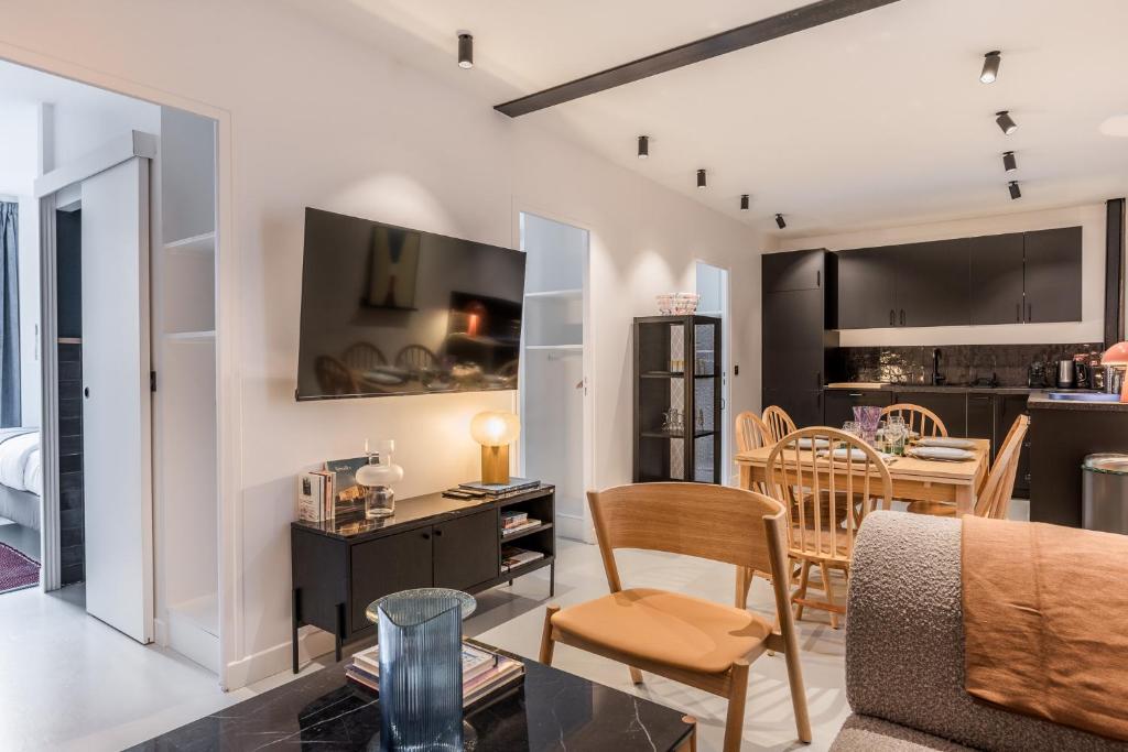 ein Wohnzimmer und eine Küche mit einem Sofa und einem Tisch in der Unterkunft Design Architect Flat - 15min. from Paris center in Gentilly