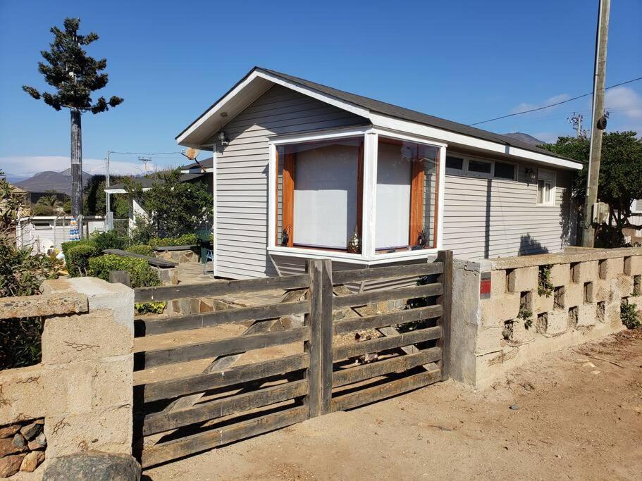 una pequeña casa con una valla delante de ella en Linda, cómoda y acogedora casa para 6, en Pichidangui