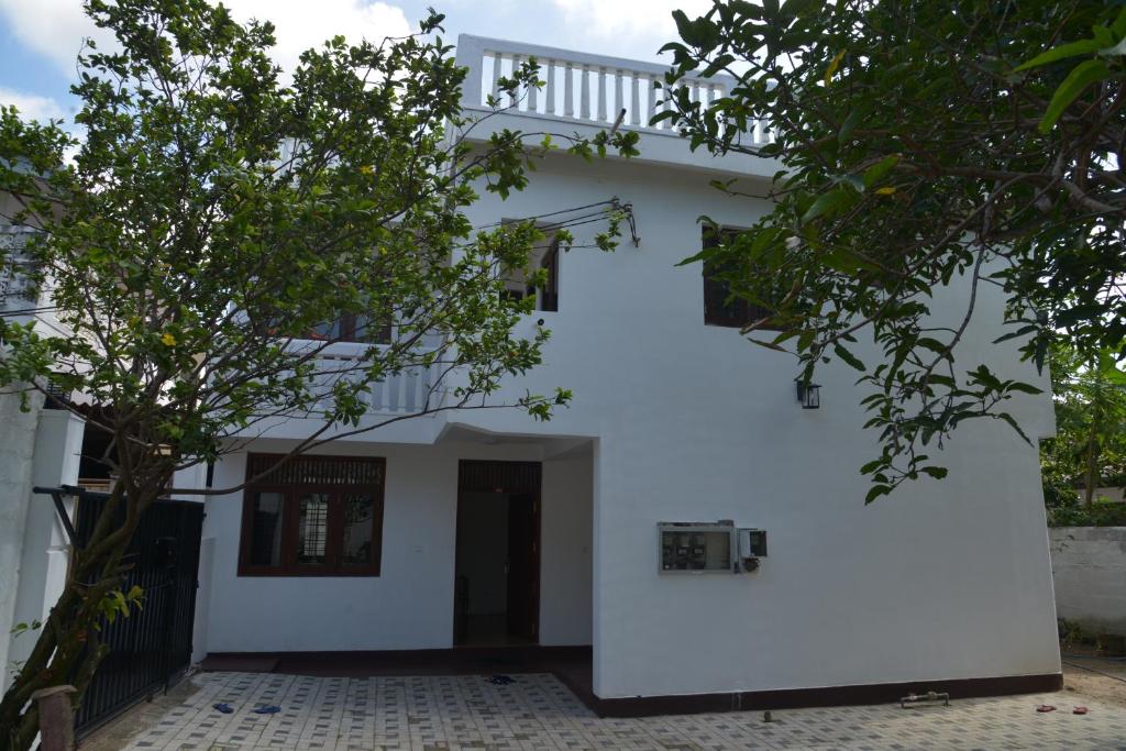 a white house with a tree in front of it at Oceanic Shades - Mount Lavinia in Mount Lavinia