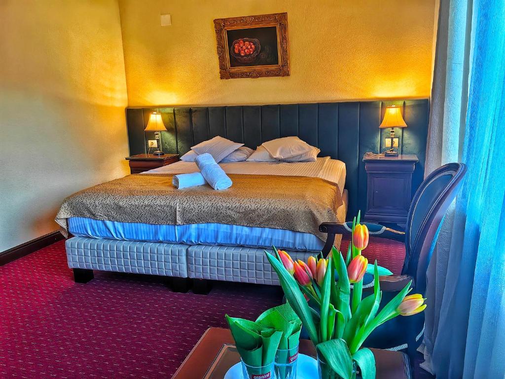 a bedroom with a bed and a table with flowers at Hotel Select in Băile Olăneşti