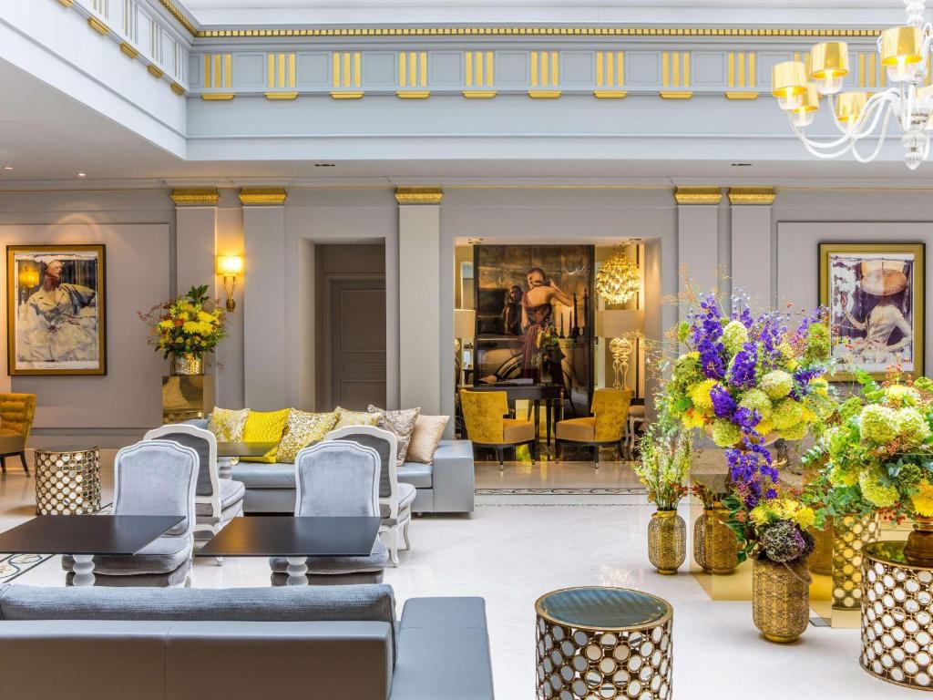 um átrio com sofás, mesas e flores em Sofitel Paris Le Faubourg em Paris