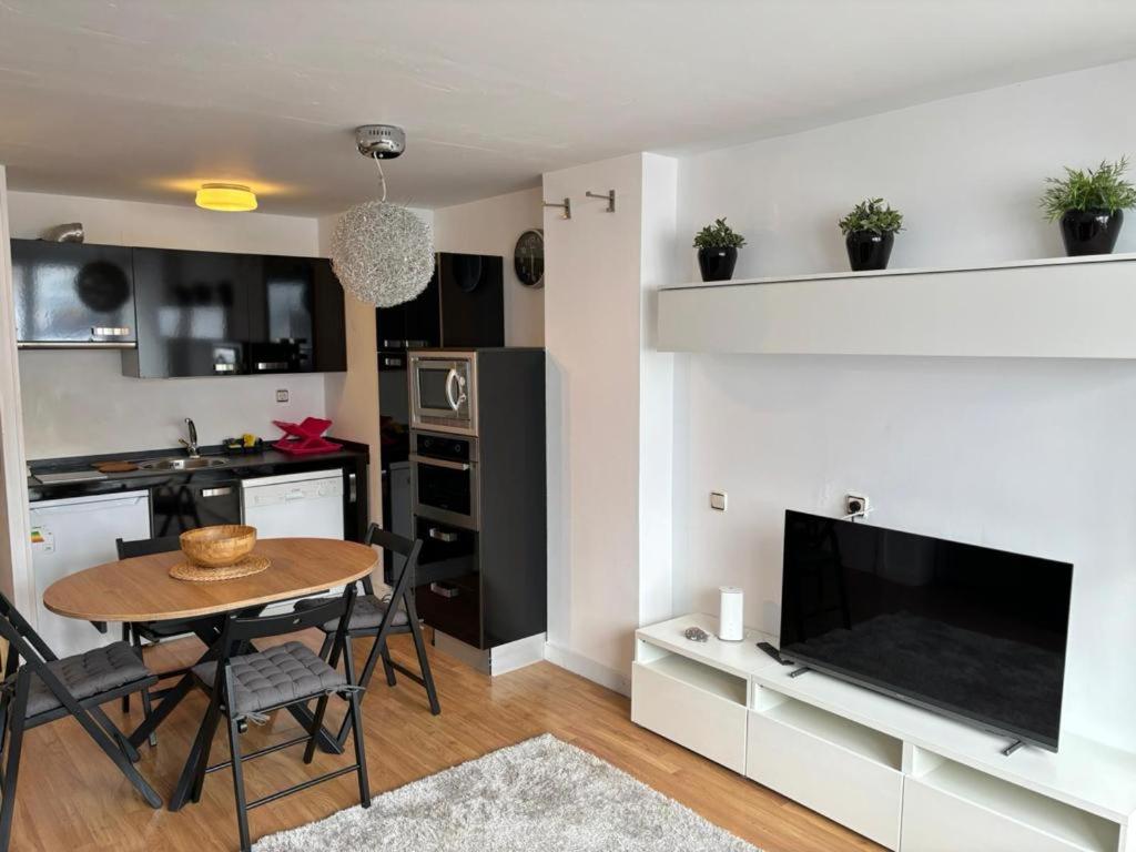 a kitchen and living room with a table and a television at Apartamento Astun in Astún