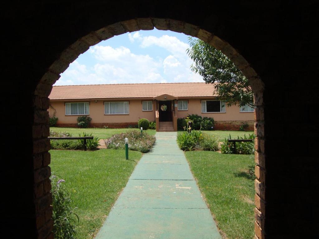 a brick archway leading to a house with a sidewalk at Gateway Guesthouse in Benoni