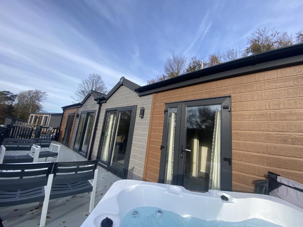 une baignoire assise sur une terrasse à côté d'un bâtiment dans l'établissement SL06 - Idwal Lodge with Hot Tub, à Bangor