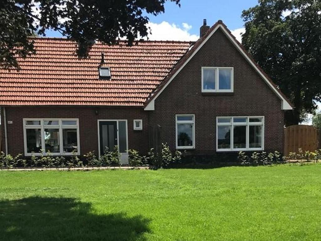 een bruin bakstenen huis met een grasveld bij Relaxing Holiday Home in Hellendoorn with Garden in Hellendoorn