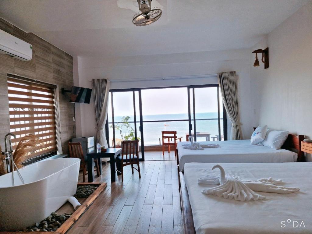 1 dormitorio con 2 camas, bañera y baño en Butterfly Rose Beach Resort Phú Quốc Francophone en Phu Quoc