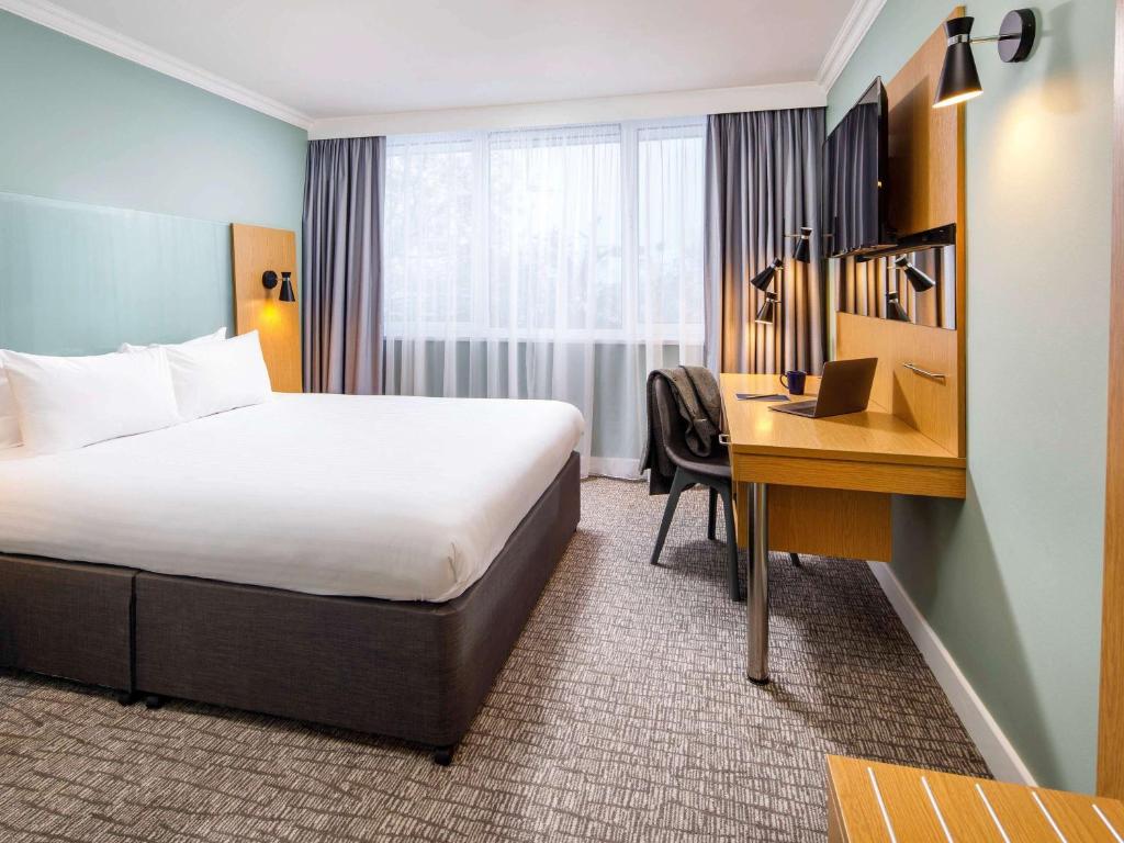 a hotel room with a bed and a desk at The Harlow Hotel By AccorHotels in Harlow