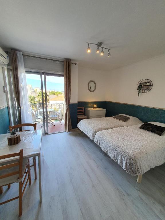 - une chambre avec 2 lits, une table et un balcon dans l'établissement Location studio meublé Curistes., à Balaruc-les-Bains