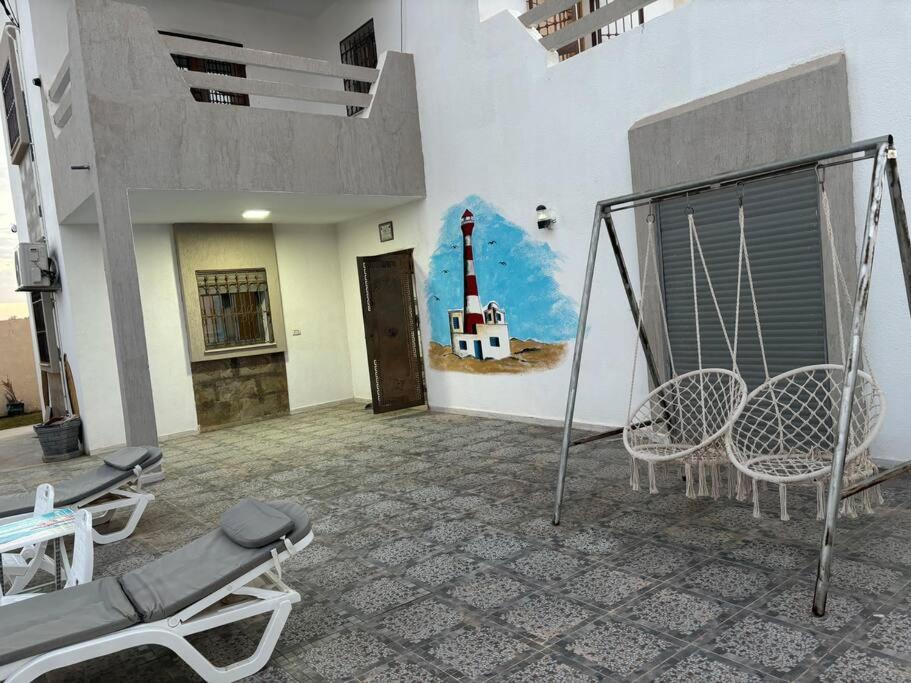 a room with chairs and a wall with a painting of a lighthouse at Villa luxe calme djerba in Midoun