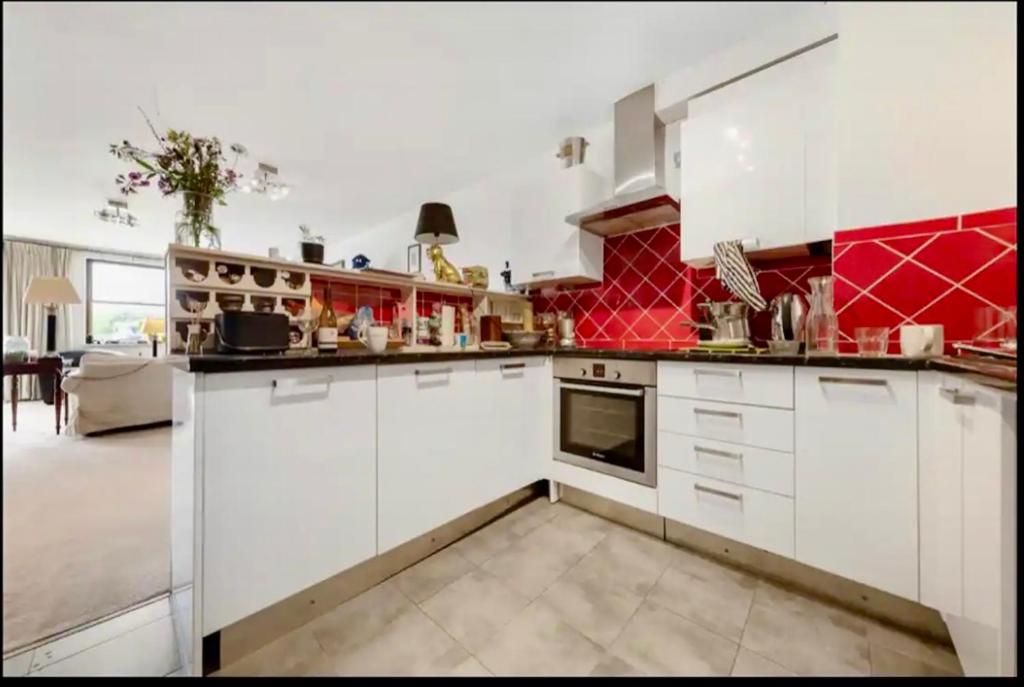 eine Küche mit weißen Schränken und roten Wänden in der Unterkunft US embassy spacious apartment nine elms in London