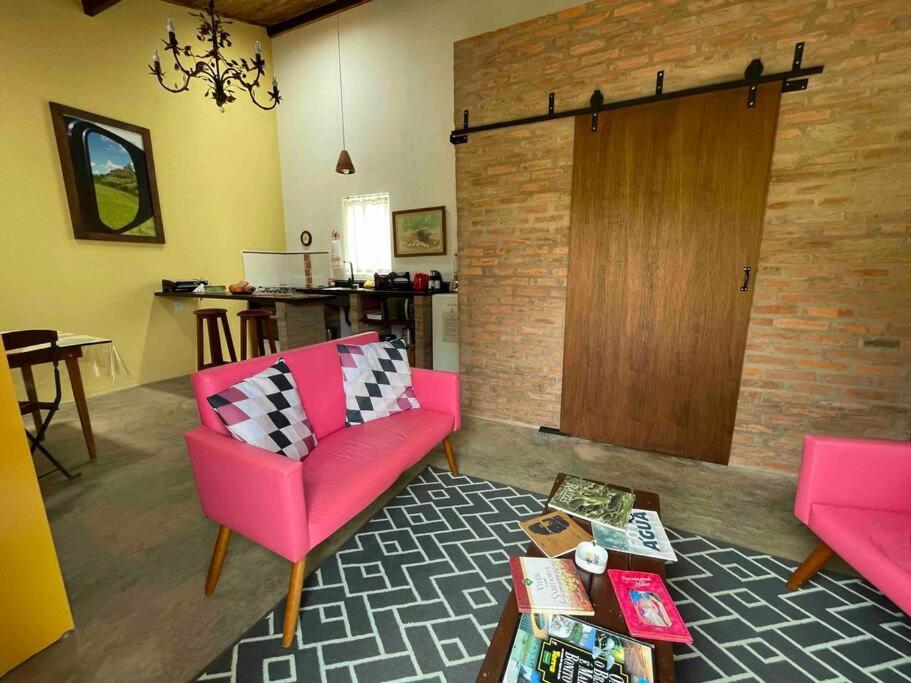 uma sala de estar com cadeiras cor-de-rosa e uma porta de madeira em Prosa & Poesia! em Botucatu