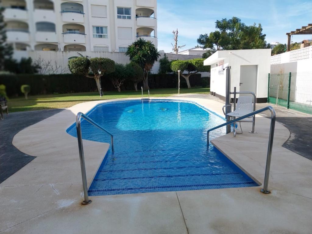 una piscina de agua azul frente a un edificio en Chalet en Málaga, Torremolinos, cerca de la playa, en Málaga