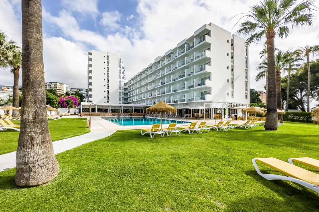 a resort with chairs and a swimming pool and palm trees at THB San Fermín in Benalmádena