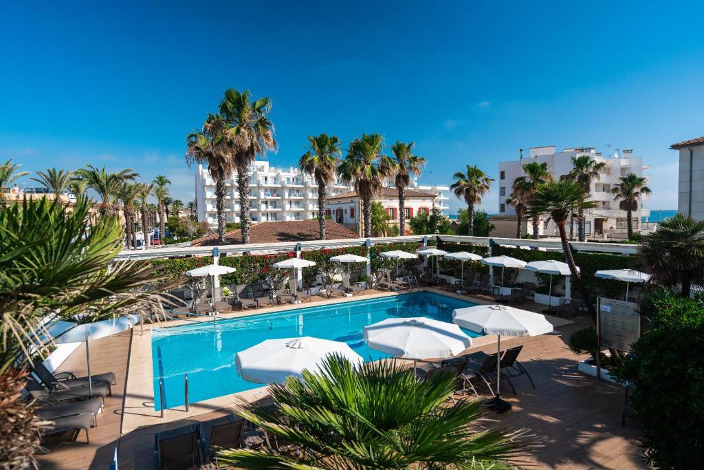 une piscine avec des parasols et des chaises et un hôtel dans l'établissement THB Gran Playa - Adults Only, à Can Picafort