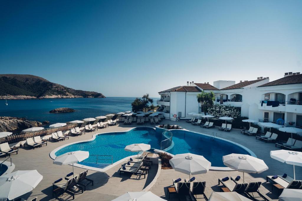 - Vistas a la piscina de un complejo con sillas y sombrillas en THB Guya Playa, en Cala Ratjada