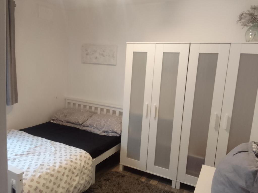 a bedroom with a bed and a white cabinet at Easy Stay in Streatham