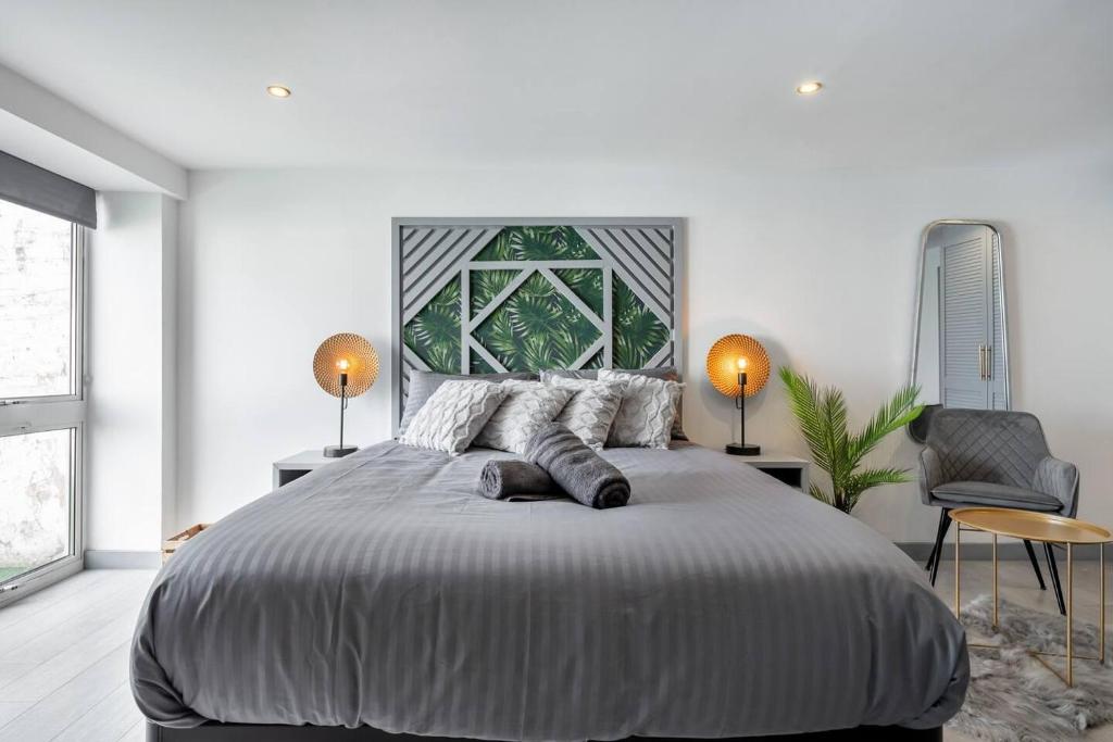 een witte slaapkamer met een groot bed en een stoel bij 5WJB - Spacious 1 Bed Flat in London in Londen