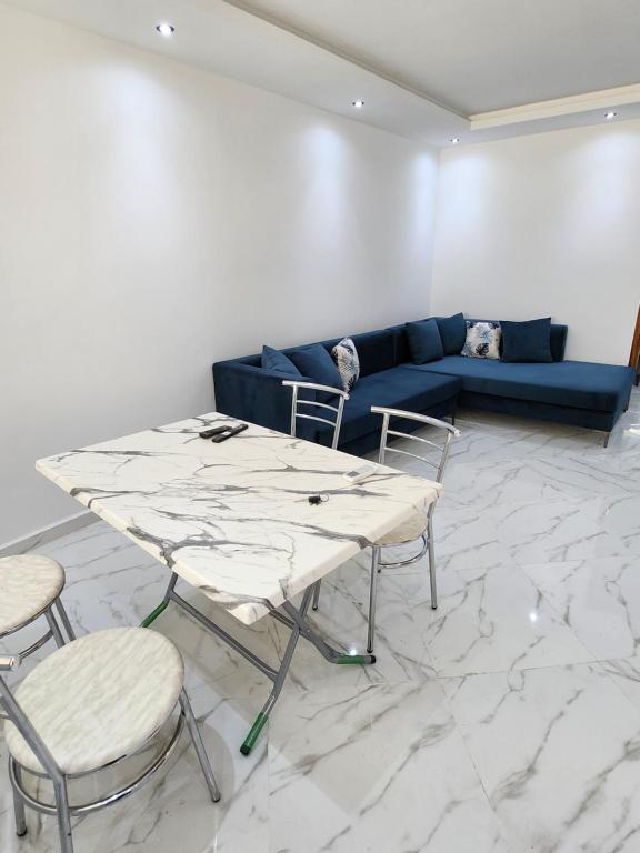 résidence el yassamine في بنزرت: غرفة معيشة مع أريكة زرقاء وطاولة وكراسي