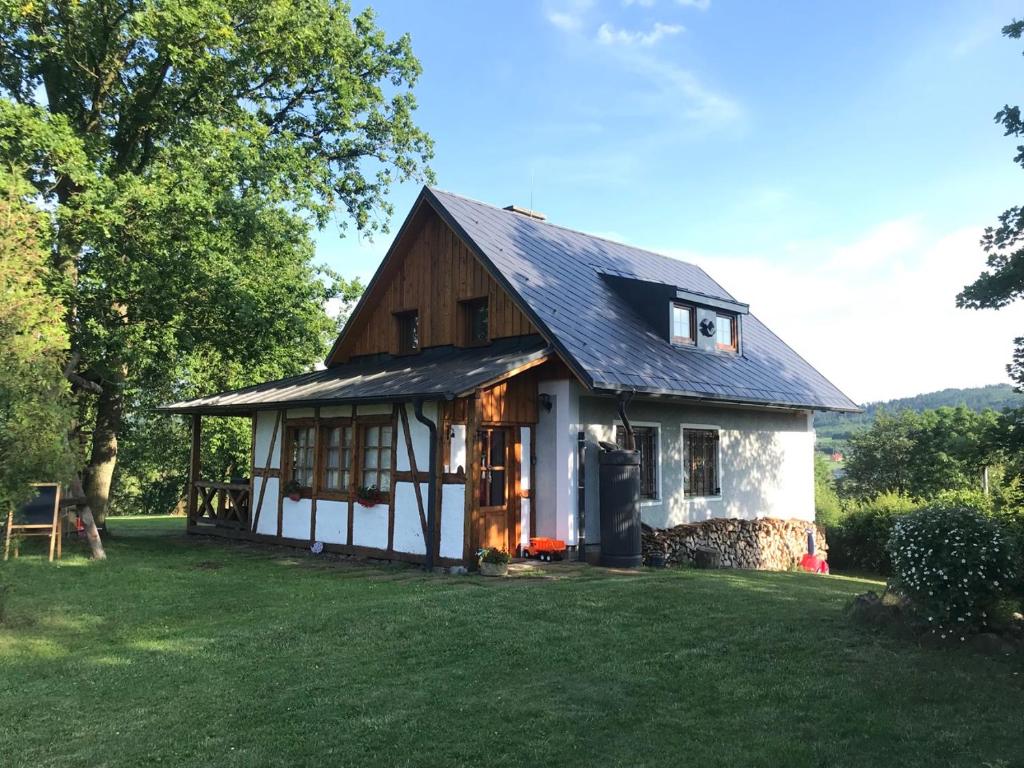 una pequeña casa blanca con techo negro en HolidayHome Sauna Kyselka, en Šemnice